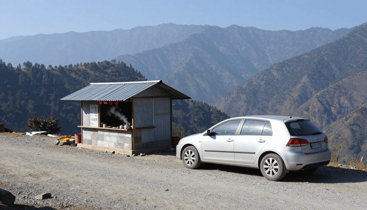 A silver hatchback parked beside a small roadside tea stall on a Himalayan mountain road, with pine covered ridges in the distance